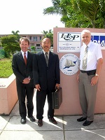 3 men pose by a wall with the sign for Anguilla Financial Services Commission