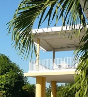 palm fronds wave in front of a 2nd storey yellow and white balcony