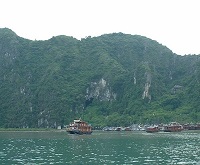 boats in a bay against a tall green hill