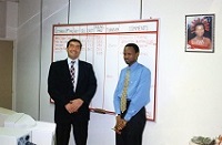 2 men smile in front of a whiteboard