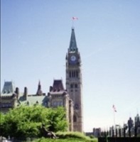 a tall stone clock tower topped with a Canadian flag
