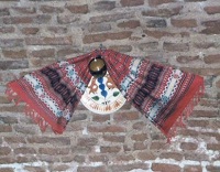 a striped fringed scarf and ceramic disc adorn a rough brick wall