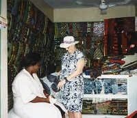 a woman browses batik material in a market vendor's booth