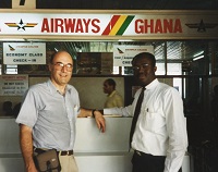 2 men smile by the Ghana Airways check in counter