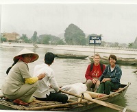 2 women smile from the front of a small rowboat during a water tour